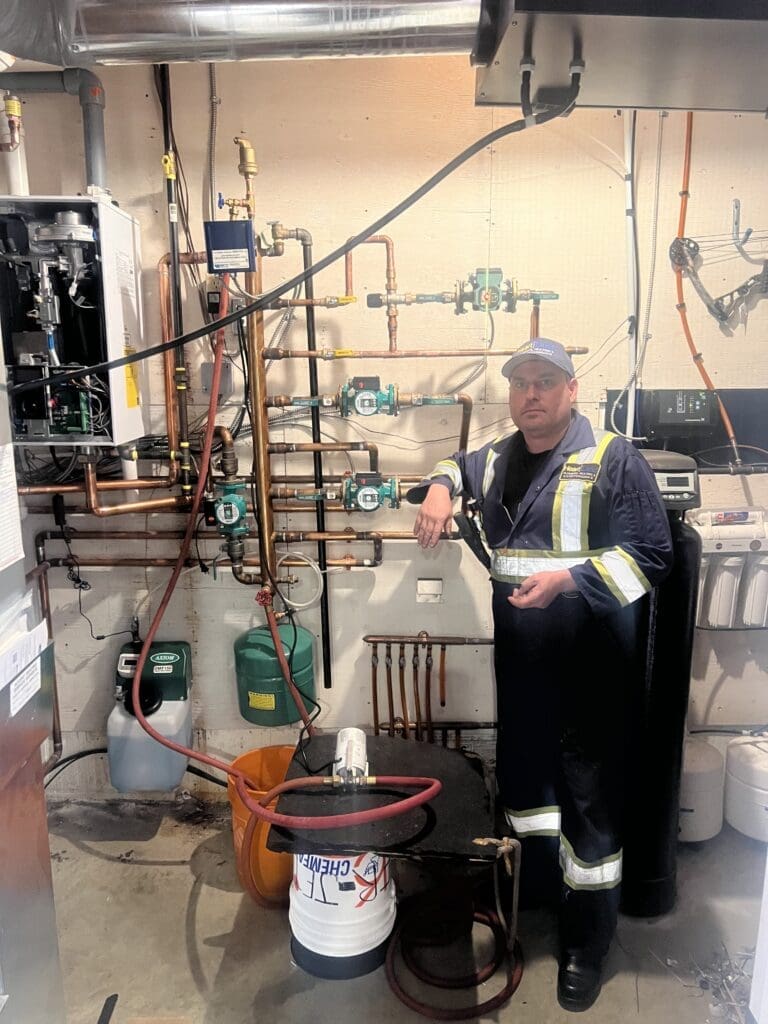 heartland-plumbing-heating-navien-boiler-replacement-35 Jaxon owner of Heartland plumbing and Heating Ltd, beside a boiler and hydronics installation